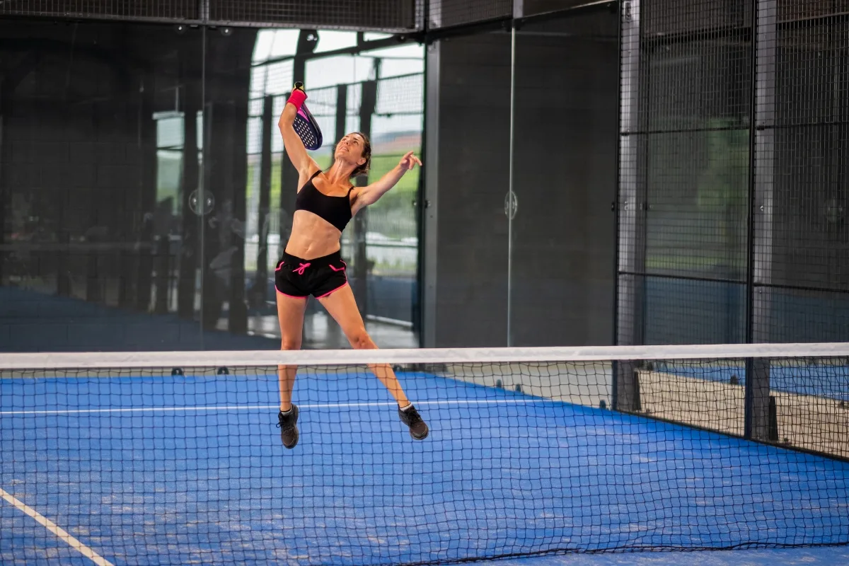 Wanita memakai crop top tanktop dan celana pendek hitam saat bermain padel