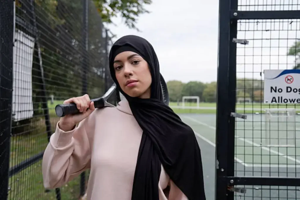 Potret perempuan Britania berjilbab sambil memegang raket padel di atas lapangan tenis